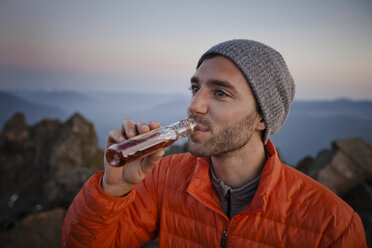 Ein Mann genießt einen Schluck Whiskey, nachdem er auf den Gipfel eines Berges gewandert ist. - AURF04072