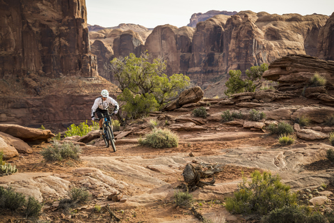 Ein Mann fährt Mountainbike in einer dramatischen Wüstenlandschaft., lizenzfreies Stockfoto