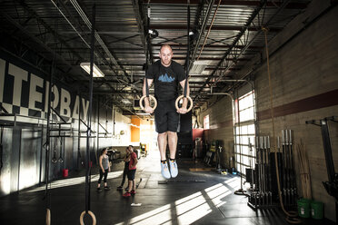 Ein Mann beim Ringtraining in einem Crossfit-Fitnessstudio. - AURF04091