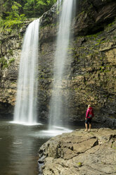 Eine Frau wandert unter einem Wasserfall im Fall Creek Falls State Park, Pikeville, Tennesee. - AURF04111