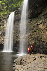 Eine Frau und ihre Tochter wandern unter einem Wasserfall im Fall Creek Falls State Park, Pikeville, Tennesee. - AURF04112