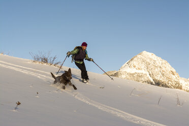 A woman and her dog skiing in the San Juan National Forest, Durango, Colorado. - AURF04117