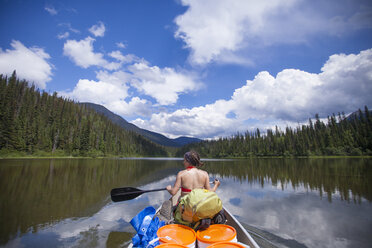 A woman paddles a canoe over Indianpoint Lake in Bowron Lake Provincial Park. - AURF04124