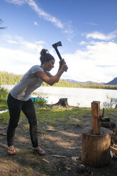 Eine Frau hackt mit einer kleinen Axt Brennholz beim Zelten am Unna Lake im Bowron Lake Provincial Park. - AURF04126