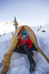 Eine junge aktive Frau posiert für ein Foto in ihrem Zelt beim Wintercamping. - AURF04128
