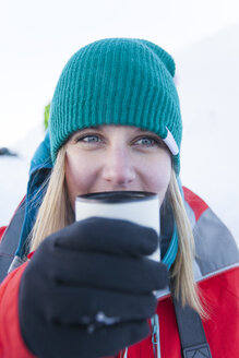 Eine junge aktive Frau genießt ein heißes Getränk während eines Wintercampingausflugs. - AURF04129
