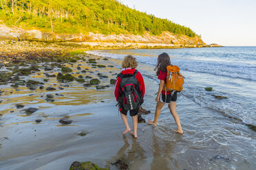 Ein Jugendlicher und ein Mädchen spazieren nach einer Wanderung im Acadia-Nationalpark in Maine am Sandstrand. - AURF04134