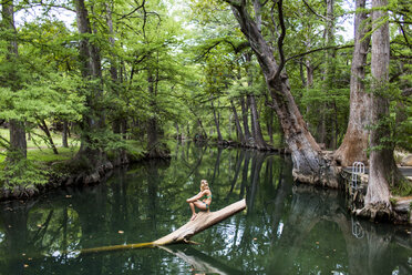 A young woman enjoys a calm swimming hole, the Blue Hole, near Wimberley, Texas. - AURF04191