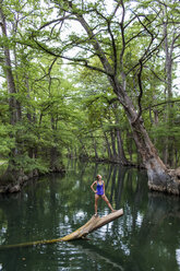 A young woman enjoys a calm swimming hole, the Blue Hole, near Wimberley, Texas. - AURF04192