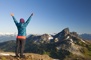 Eine junge Frau jubelt, nachdem sie den Gipfel des Panorama Ridge im Garibaldi Provincial Park, British Columbia, Kanada, erreicht hat. - AURF04217