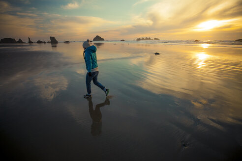 Eine junge Frau geht am Strand von Bandon, Oregon, spazieren. - AURF04222