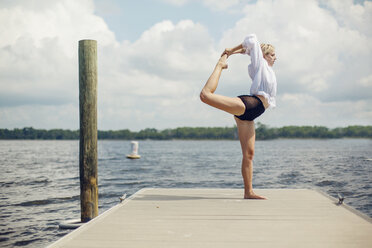A young woman does yoga on a pier. - AURF04232