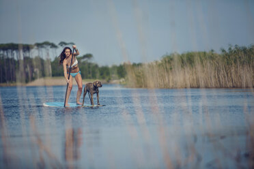 Eine junge Frau und ihr Hund beim SUP am Grayton Beach. - AURF04240