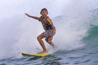 Asiatischer Junge surft auf einer Welle. - AURF04337