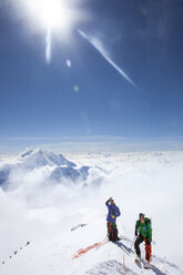 Die Bergsteiger und Ranger Dave Weber und Tom Ditolla befinden sich auf einem Schneekamm der Westrippe hoch oben auf dem Mount McKinley. Dave zeigt auf den Gipfel, Mount Hunter ist im Hintergrund zu sehen. - AURF04345