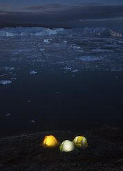 Camping tents at night on shore of Ilulissat Icefjord, Greenland, Denmark - AURF04346