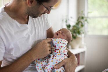 Ein Vater wickelt sein Baby zu Hause in eine Decke - AURF04437