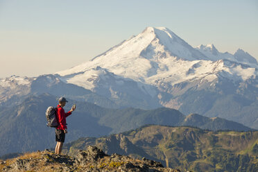 A Backpacker Checks His Phone While Hiking In North Cascades National Park - AURF04442