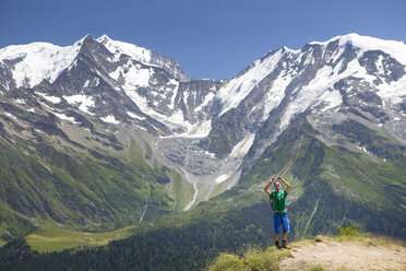 Ein männlicher Wanderer macht ein Foto mit seinem Smartphone auf dem Gipfel des Mont Joly, im Hintergrund der Mont Blanc. - AURF04471