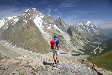 Ein männlicher Wanderer blickt über das Val Veny in der Nähe von Courmayeur, wobei der Mont Blanc die Himmelslinie dominiert. - AURF04473