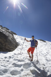 Ein männlicher Wanderer steigt im Sommer über ein Schneefeld ab. Einige schattige Abschnitte der Haute Route bleiben das ganze Jahr über kalt. - AURF04475