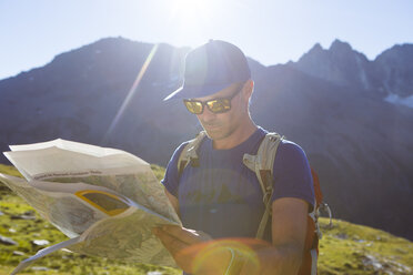 Ein männlicher Wanderer schaut auf eine Karte, um seinen Weg durch die Berge zu finden - AURF04477