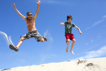 Ein Mann und ein Junge springen auf einer Sanddüne in Provincetown, MA. - AURF04486