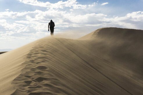 A hiker walking a ridge line in the sand dunes - AURF04494