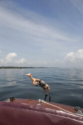 Ein Mann springt von einem antiken Holzboot auf dem Sankt-Lorenz-Strom in den 1000 Inseln im Bundesstaat New York. - AURF04516