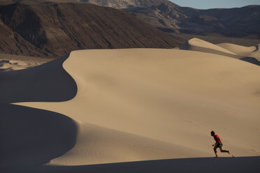 A man running on sand dunes in the desert. - AURF04521