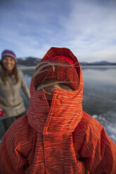 A mom smiles on behind her daughter, all bundled-up for ice skating on a cold winter's day. - AURF04523