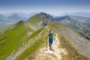 A solo male hiker on a mountain ridge near Mont Joly in France, halfway the Tour du Mont Blanc. - AURF04529