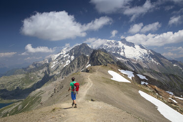 A solo male hiker is walking on the ridge of the Tete des Fours with Mont Blanc in the distance. - AURF04530