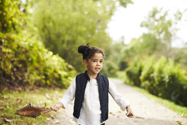 Ein Porträt eines kleinen Mädchens, das mit einem großen Blatt spielt. - AURF04540