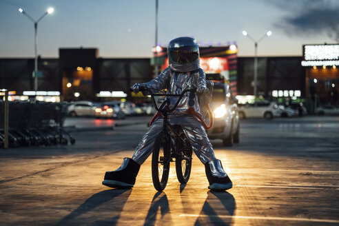 Spaceman in der Stadt bei Nacht auf Parkplatz mit bmx Fahrrad - VPIF00669
