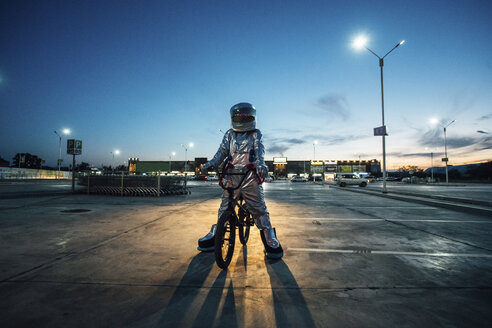 Spaceman in the city at night on parking lot with bmx bike - VPIF00670