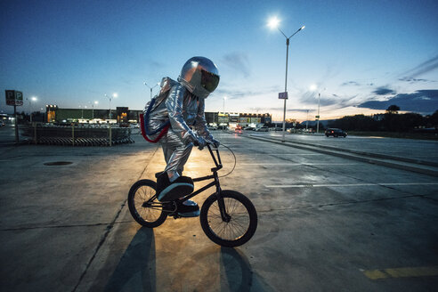 Spaceman in the city at night on parking lot riding bmx bike - VPIF00671