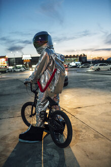 Spaceman in der Stadt bei Nacht auf Parkplatz mit bmx Fahrrad - VPIF00673