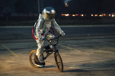 Spaceman in der Stadt bei Nacht auf dem Parkplatz fahren bmx Fahrrad, lizenzfreies Stockfoto
