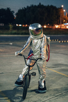 Spaceman in the city at night on parking lot with bmx bike - VPIF00677