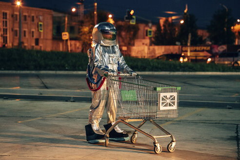 Raumfahrer in der Stadt bei Nacht auf Parkplatz mit Einkaufswagen - VPIF00678