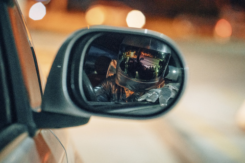 Reflexion des Raumfahrers im Außenspiegel eines Autos bei Nacht, lizenzfreies Stockfoto