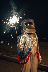 Raumfahrer steht nachts im Freien und hält eine Wunderkerze - VPIF00699