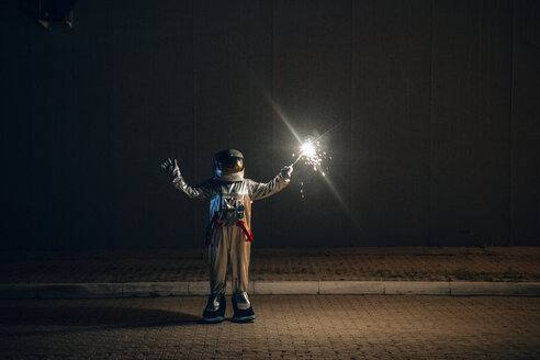 Spaceman standing on a road at night holding sparkler - VPIF00705