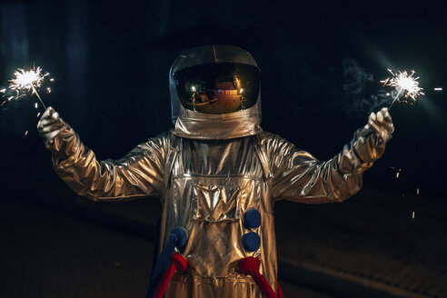 Spaceman standing on a road at night holding sparklers - VPIF00707