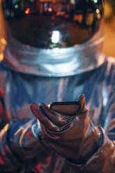 Spaceman outdoors at night using smartphone - VPIF00724