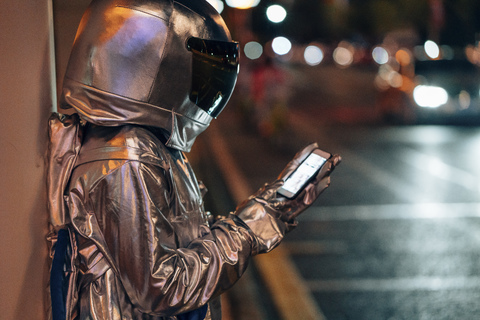 Raumfahrer auf einer nächtlichen Straße mit Mobiltelefon, lizenzfreies Stockfoto