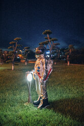 Spaceman standing at a lamp in a park at night - VPIF00742