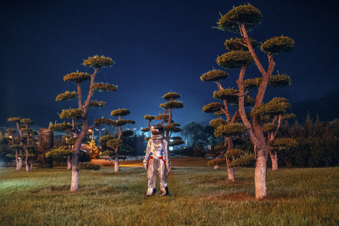 Spaceman standing in a park at night stock photo