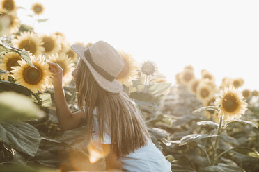 Porträt einer jungen Frau, die in einem Sonnenblumenfeld steht - OCAF00359